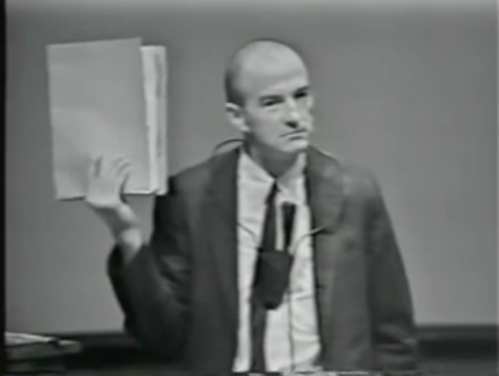 Black-and-white photograph of a lecturer beside a blackboard.